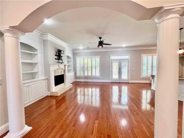 unfurnished living room with light hardwood / wood-style floors, built in features, and ornate columns