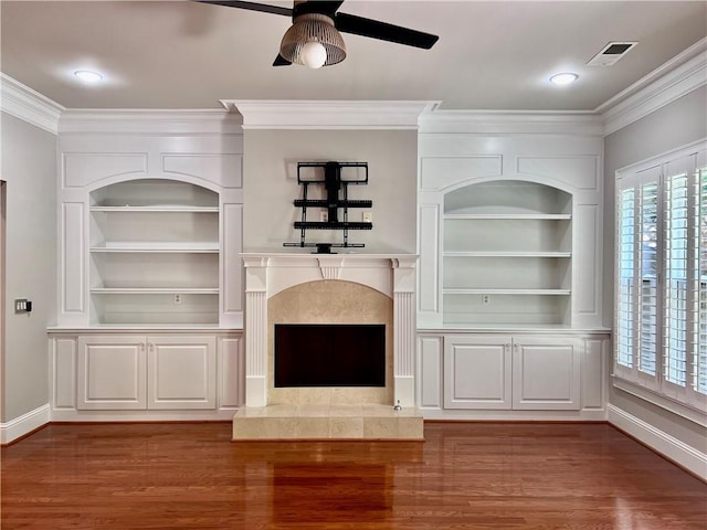 unfurnished living room featuring hardwood / wood-style flooring, ornamental molding, built in features, and ceiling fan