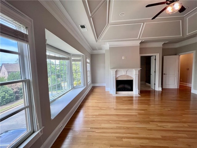 unfurnished living room featuring ornamental molding, coffered ceiling, ceiling fan, a high end fireplace, and light wood-type flooring