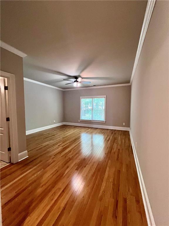 empty room with hardwood / wood-style floors, crown molding, and ceiling fan