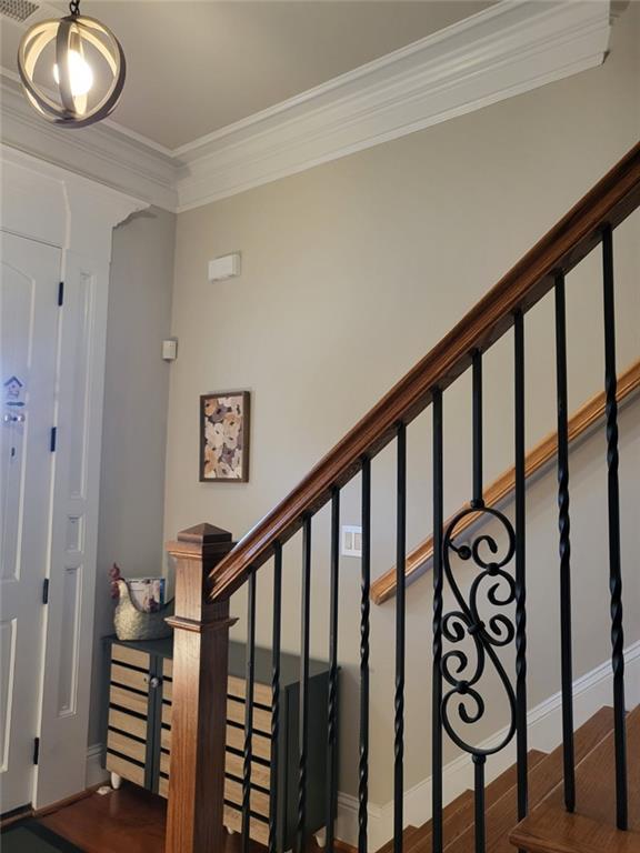 stairs with ornamental molding and wood-type flooring