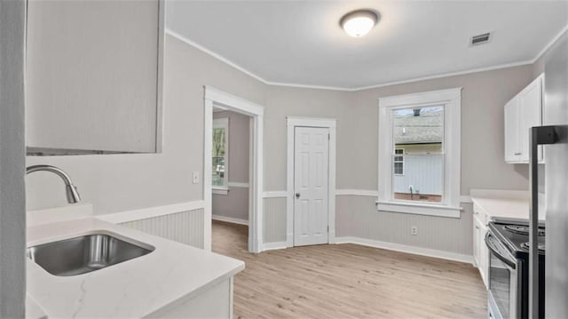 kitchen featuring sink, crown molding, light wood-type flooring, electric stove, and white cabinets