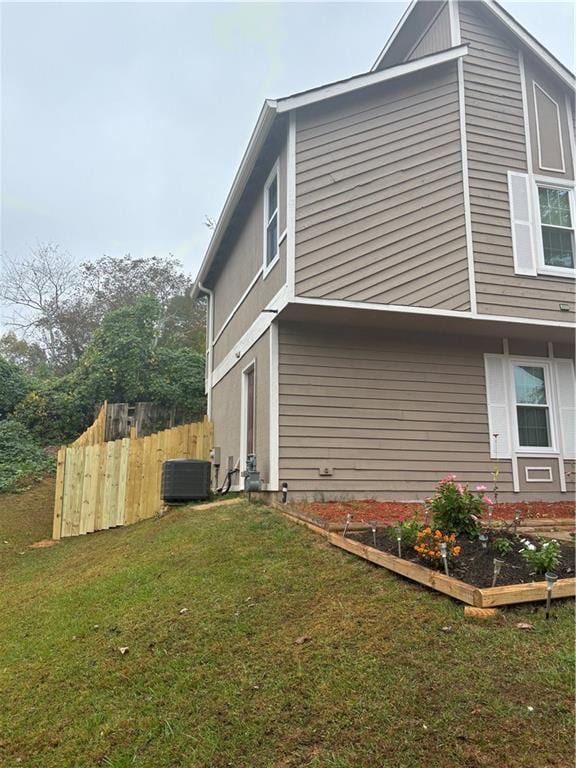 view of side of home featuring central AC and a lawn