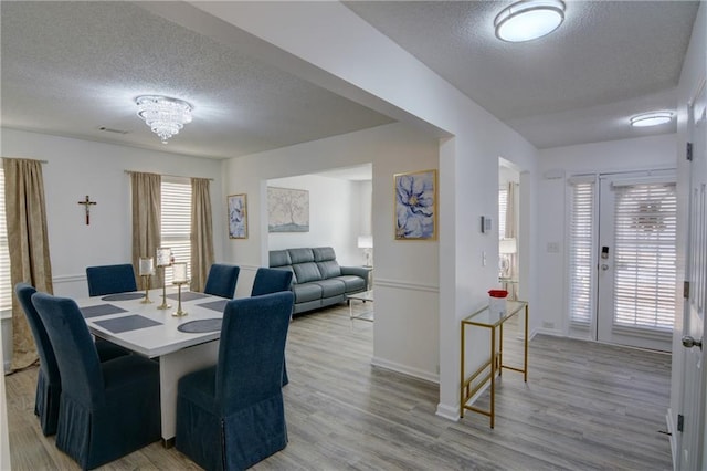 dining area featuring light wood finished floors and a textured ceiling