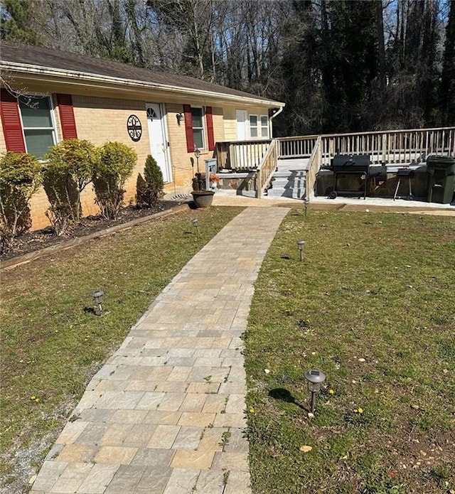 view of front of property with brick siding, a wooden deck, and a front yard