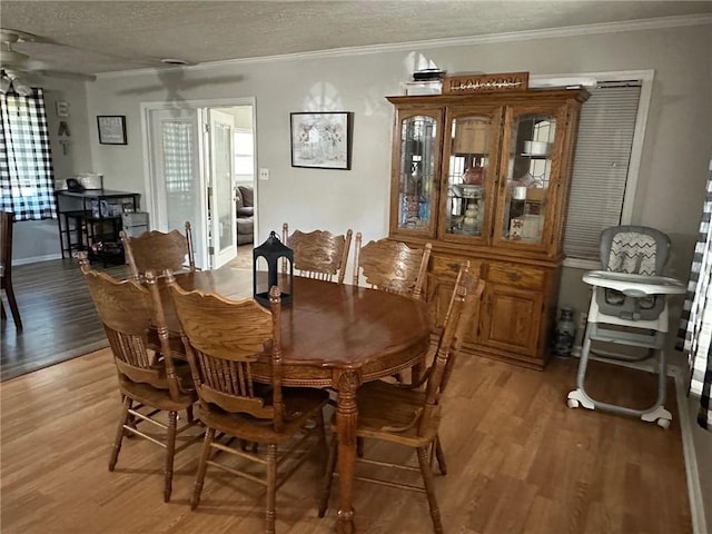 dining space featuring a textured ceiling, light wood-type flooring, and ornamental molding