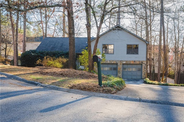 view of front facade with a garage, stone siding, roof with shingles, and driveway