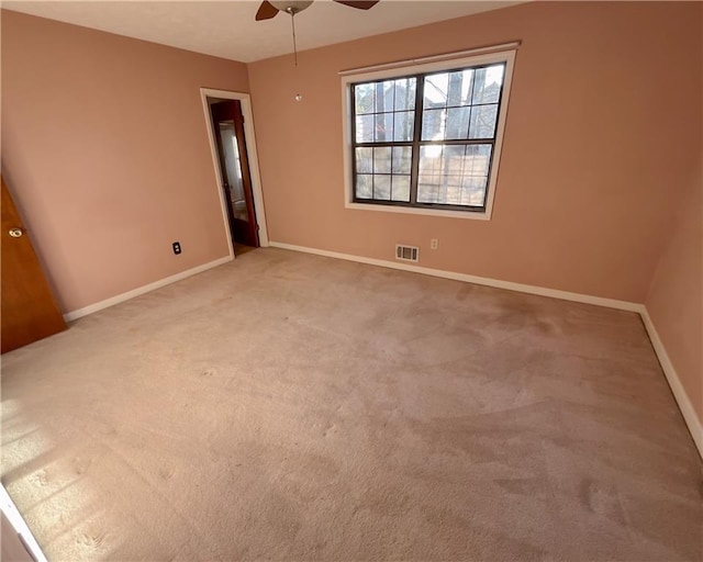 carpeted empty room with a ceiling fan, visible vents, and baseboards