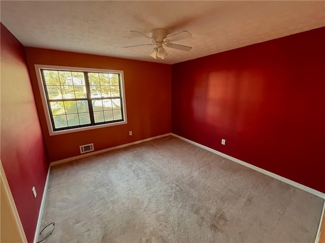 spare room featuring carpet, visible vents, a textured ceiling, and baseboards