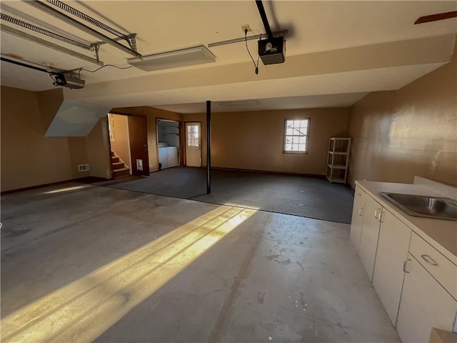 garage with a garage door opener, a sink, and independent washer and dryer