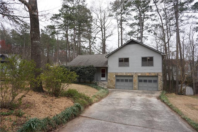 split level home with stone siding, driveway, roof with shingles, and an attached garage