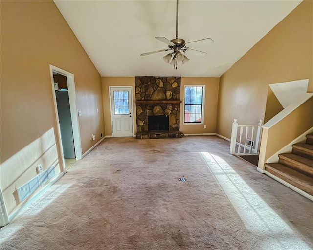 unfurnished living room with a ceiling fan, stairs, carpet flooring, a stone fireplace, and high vaulted ceiling