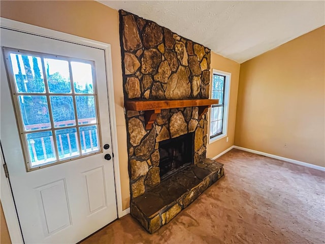 carpeted living area with baseboards, a textured ceiling, and a stone fireplace