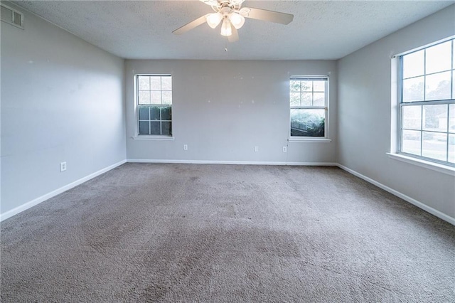 carpeted spare room featuring plenty of natural light, ceiling fan, and a textured ceiling