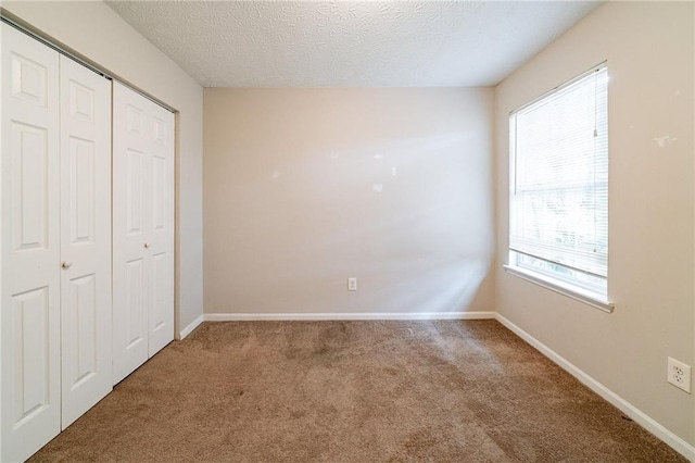 unfurnished bedroom with carpet flooring, a textured ceiling, and a closet