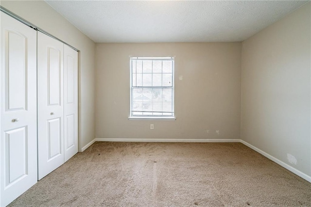 unfurnished bedroom featuring a closet, light colored carpet, and a textured ceiling