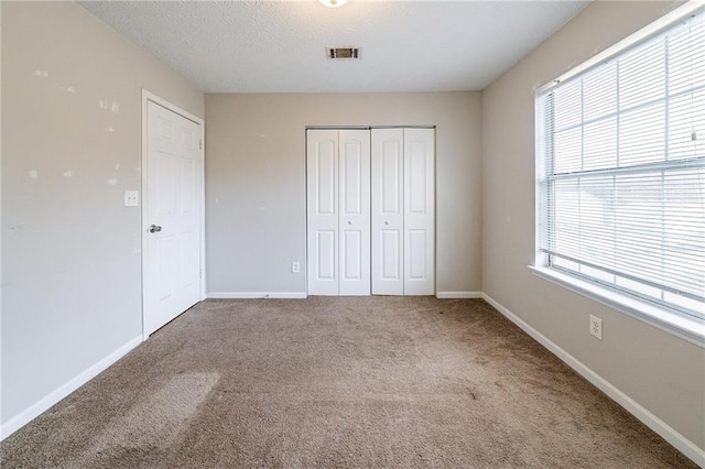 unfurnished bedroom featuring carpet floors, a closet, and multiple windows