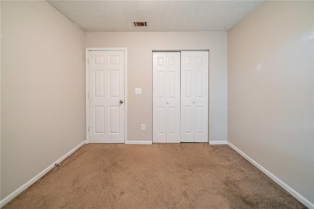 unfurnished bedroom featuring a closet, carpet, and a textured ceiling