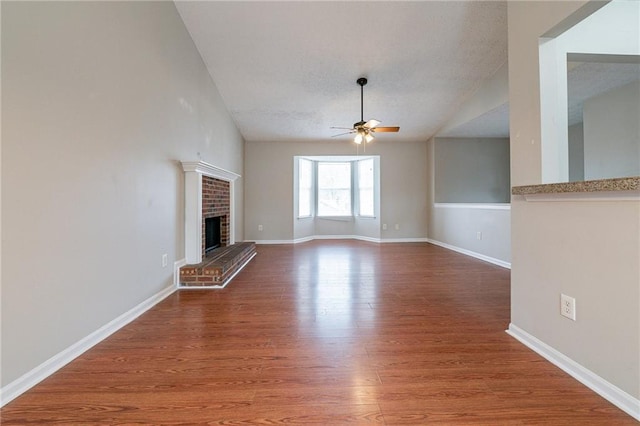 unfurnished living room with hardwood / wood-style flooring, ceiling fan, a fireplace, and a textured ceiling