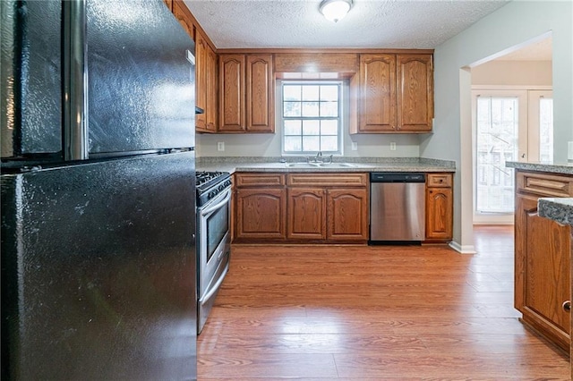 kitchen with french doors, light wood-type flooring, a textured ceiling, stainless steel appliances, and sink