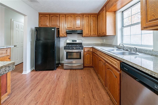 kitchen featuring sink, light hardwood / wood-style floors, a textured ceiling, and appliances with stainless steel finishes