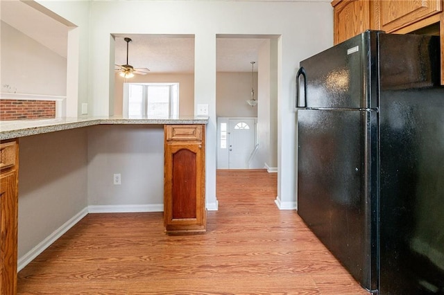 kitchen with light hardwood / wood-style flooring, black fridge, and ceiling fan