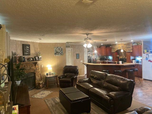 1167 Underwood Rd, Sparta, GA 31087 - living area featuring a textured ceiling, a ceiling fan, and a stone fireplace