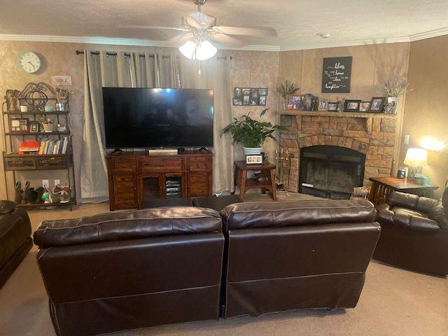 1167 Underwood Rd, Sparta, GA 31087 - carpeted living area with a ceiling fan, crown molding, and a stone fireplace