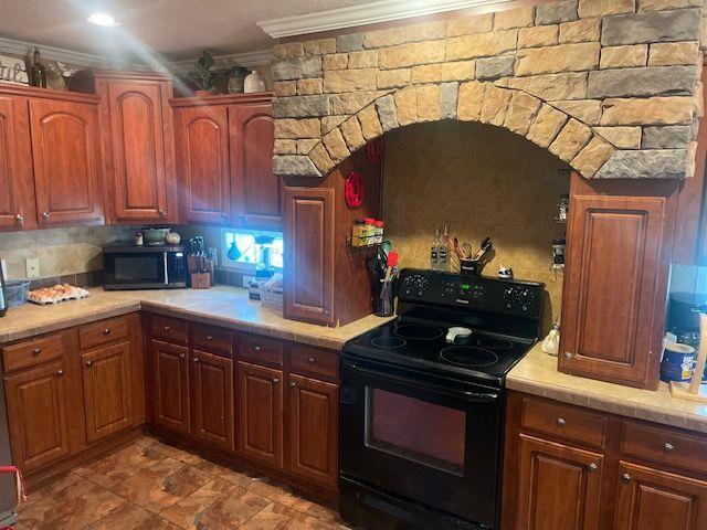 1167 Underwood Rd, Sparta, GA 31087 - kitchen featuring black / electric stove, ornamental molding, and tile counters