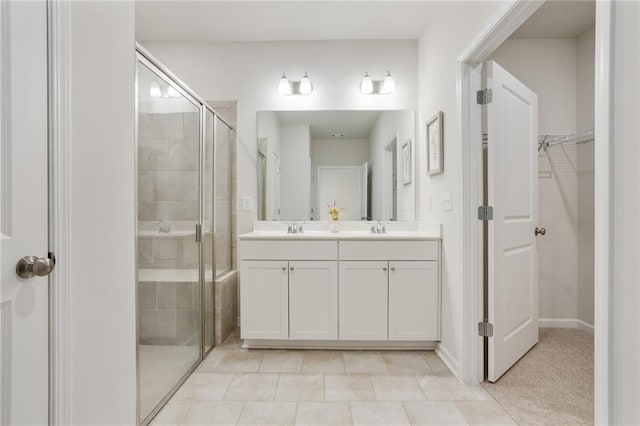 bathroom featuring a spacious closet, double vanity, a stall shower, and a sink