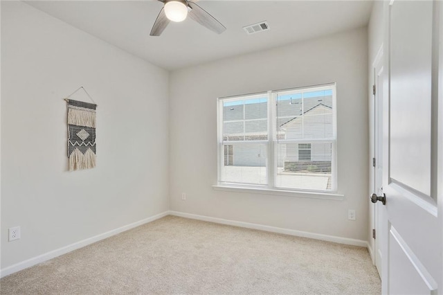 spare room with baseboards, ceiling fan, visible vents, and light colored carpet