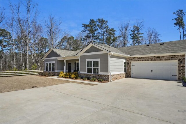 view of front of property with concrete driveway, brick siding, an attached garage, and fence