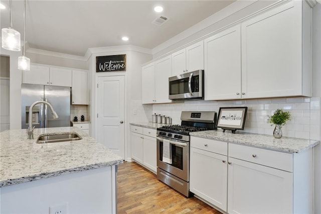 kitchen with stainless steel appliances, white cabinetry, light wood-style flooring, and decorative light fixtures