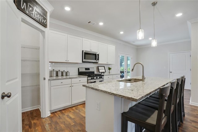 kitchen featuring an island with sink, white cabinets, stainless steel appliances, and a sink