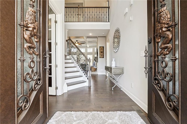 foyer with coffered ceiling, baseboards, stairs, beam ceiling, and dark wood-style floors