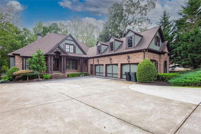 view of front facade featuring a garage, brick siding, a chimney, and driveway