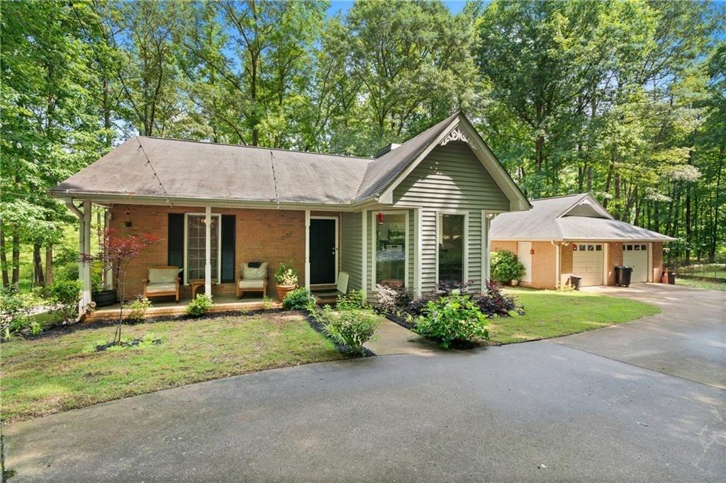 view of front of property featuring covered porch, a front yard, and a garage