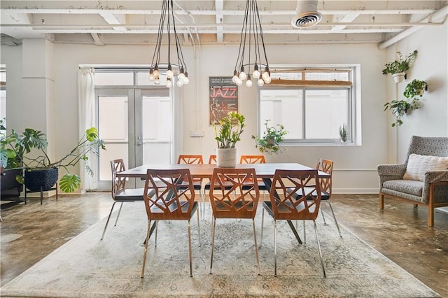 dining room featuring concrete flooring, french doors, and an inviting chandelier