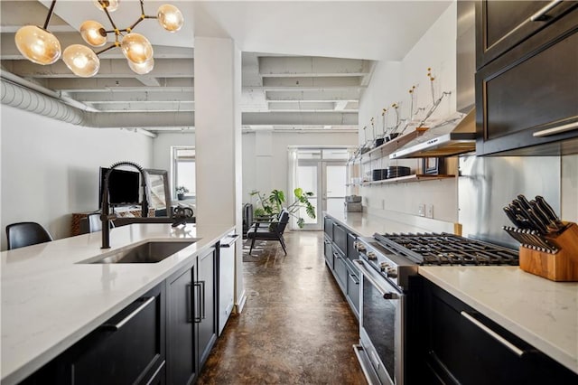 kitchen featuring light stone countertops, high end stove, sink, an inviting chandelier, and hanging light fixtures