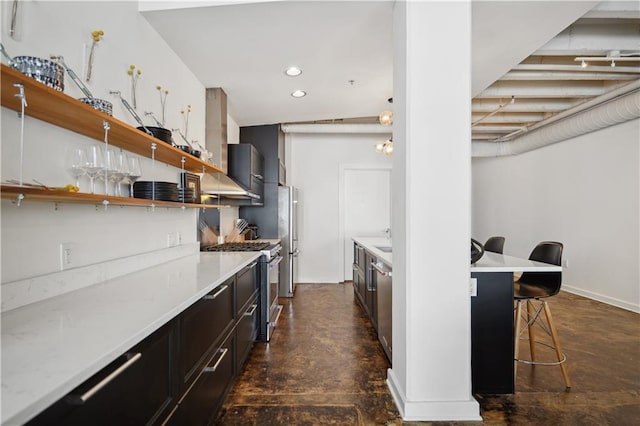 kitchen featuring a kitchen bar, wall chimney exhaust hood, and stainless steel appliances