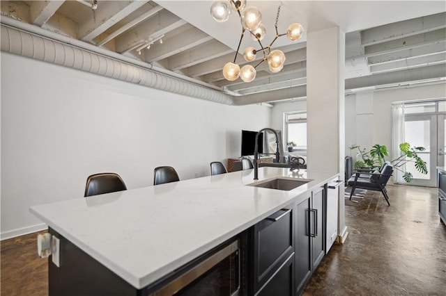 kitchen with sink, a kitchen breakfast bar, a chandelier, decorative light fixtures, and a kitchen island with sink