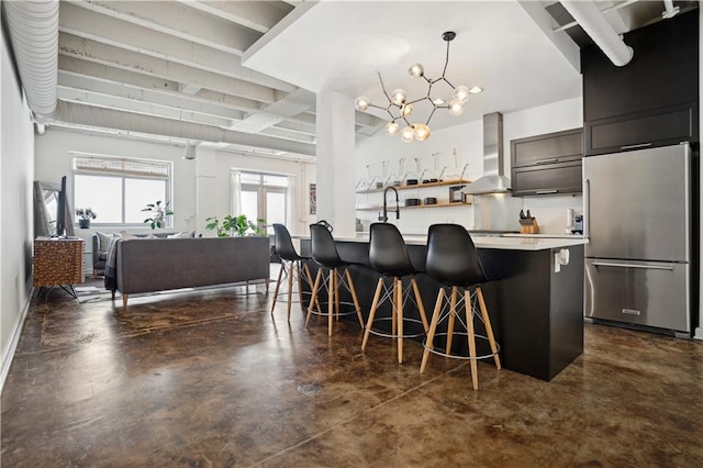 kitchen featuring an inviting chandelier, hanging light fixtures, wall chimney exhaust hood, high quality fridge, and a breakfast bar area