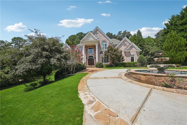 view of front facade featuring driveway, a front lawn, and brick siding