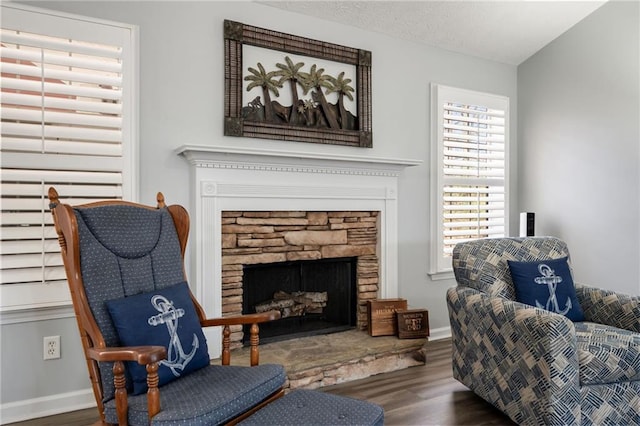 sitting room featuring hardwood / wood-style floors, a stone fireplace, and a textured ceiling