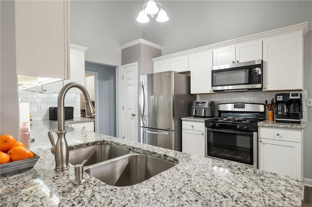 kitchen featuring sink, white cabinetry, appliances with stainless steel finishes, light stone countertops, and decorative backsplash