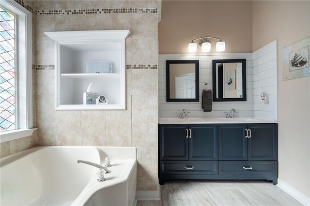 bathroom featuring vanity, a bath, a wealth of natural light, and tile walls