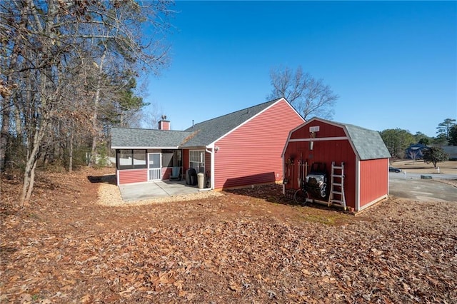 rear view of house featuring a patio, an outdoor structure, and a sunroom