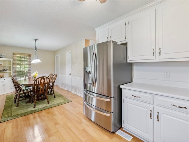 5020 Bayberry Dr, Cumming, GA 30040 - kitchen featuring stainless steel fridge with ice dispenser, white cabinets, light countertops, light wood-style floors, and decorative light fixtures