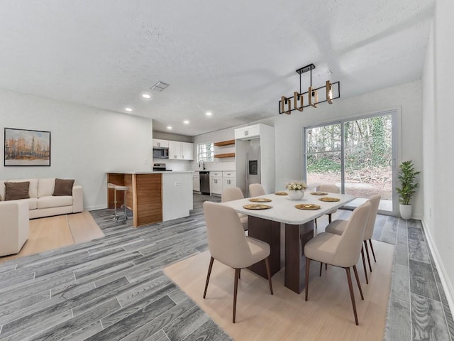 dining room with light wood-type flooring and a textured ceiling