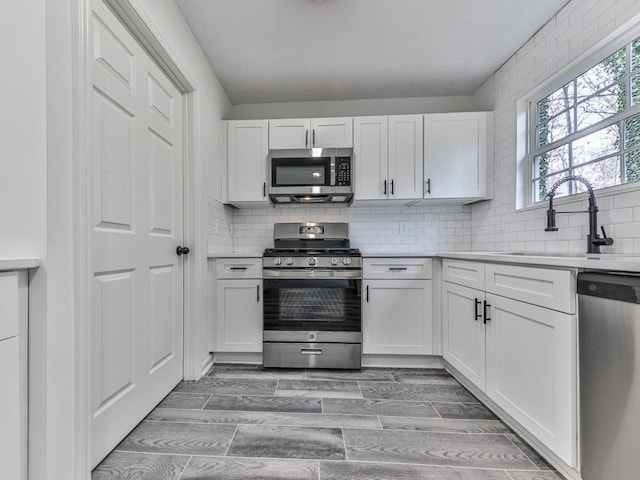 kitchen featuring white cabinets, appliances with stainless steel finishes, hardwood / wood-style flooring, and sink